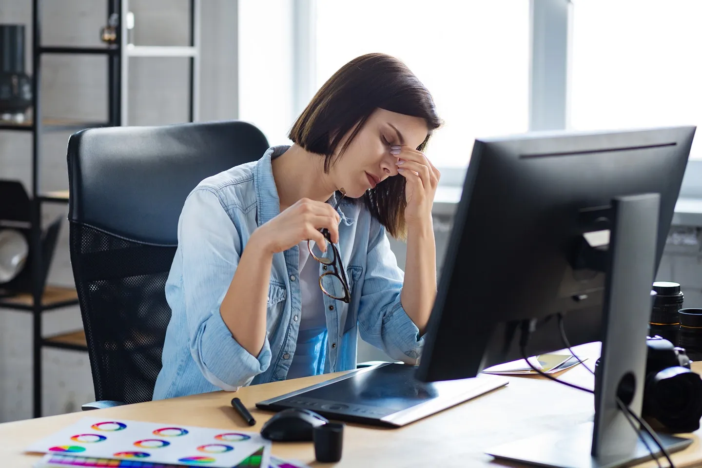 A woman looking stressed at her desk.