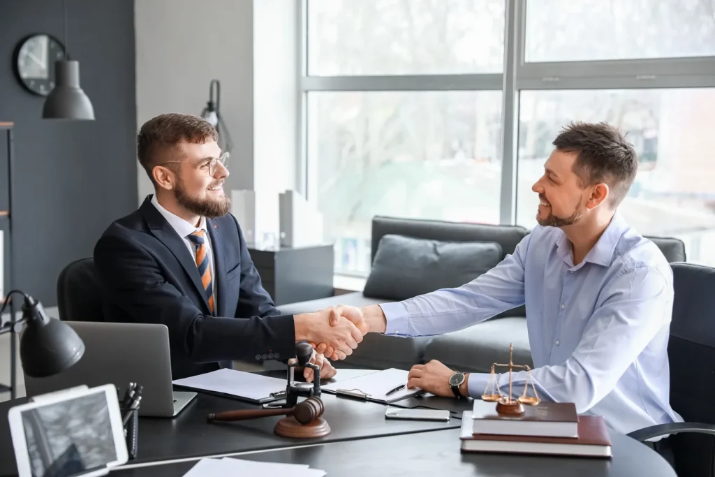 Two men shaking hands over a desk.