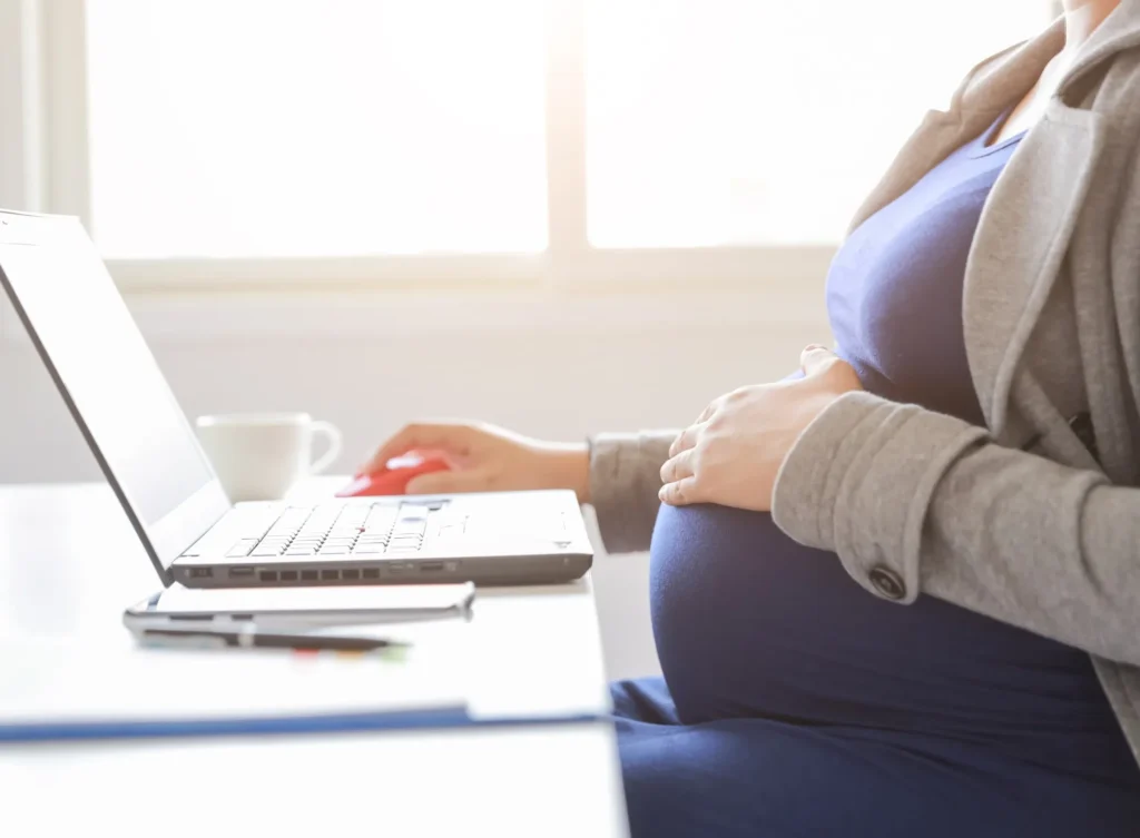 A pregnant woman working at her computer.