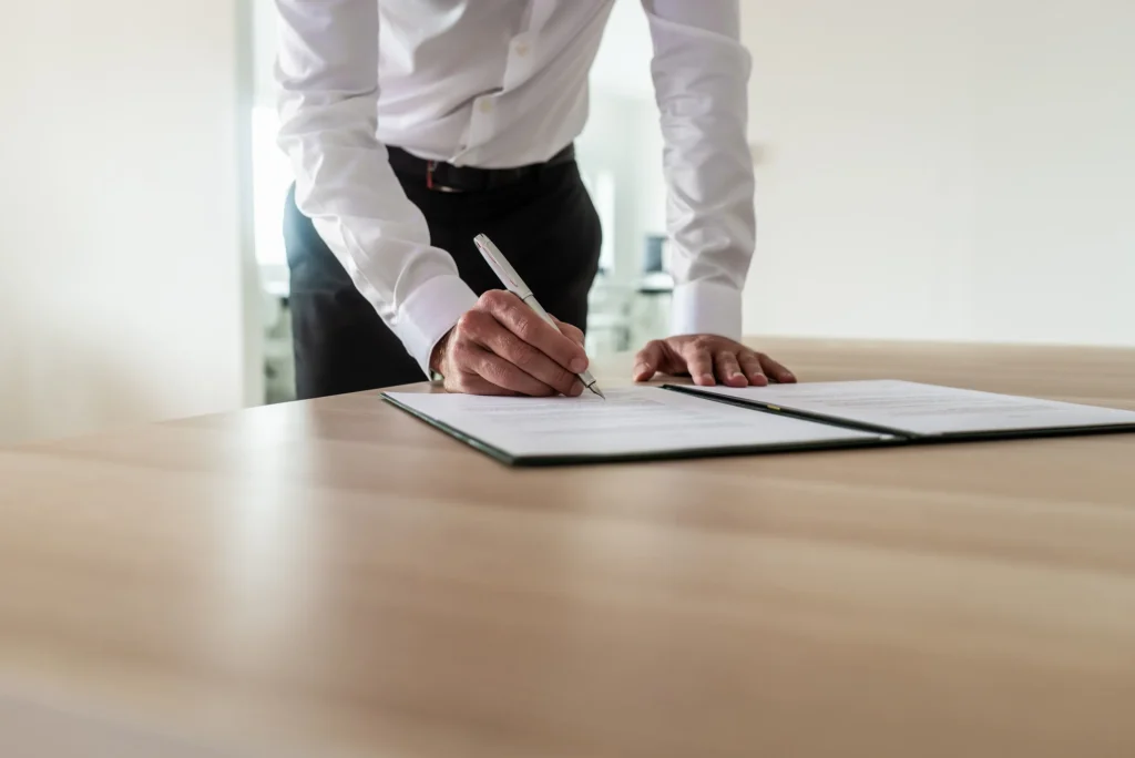 Man standing at desk signing paperwork.