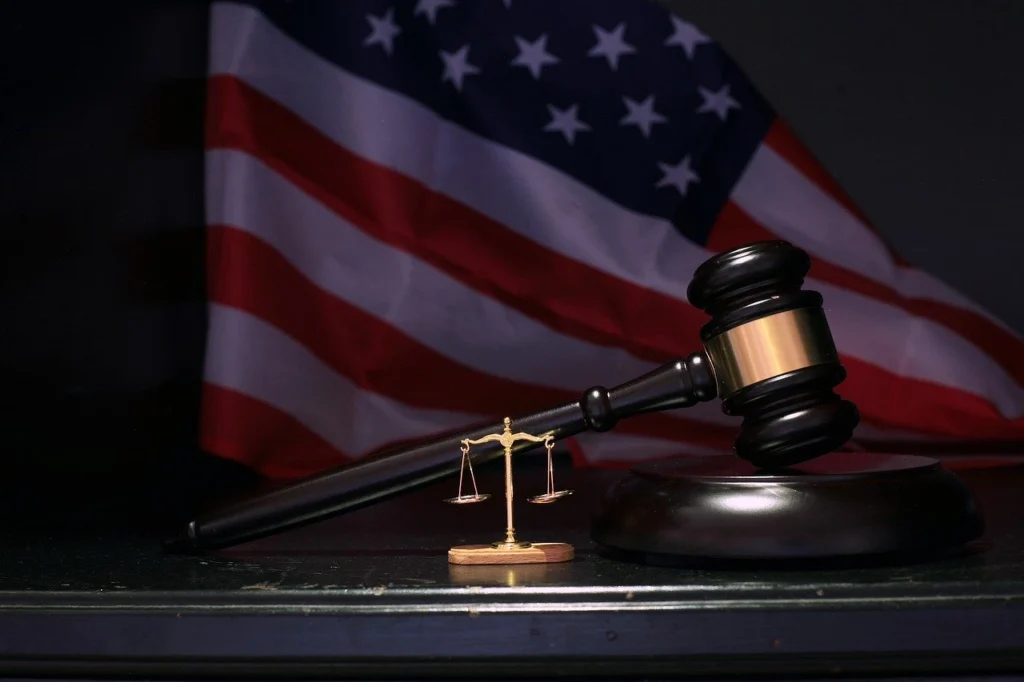 A dark gavel sitting in front of the american flag
