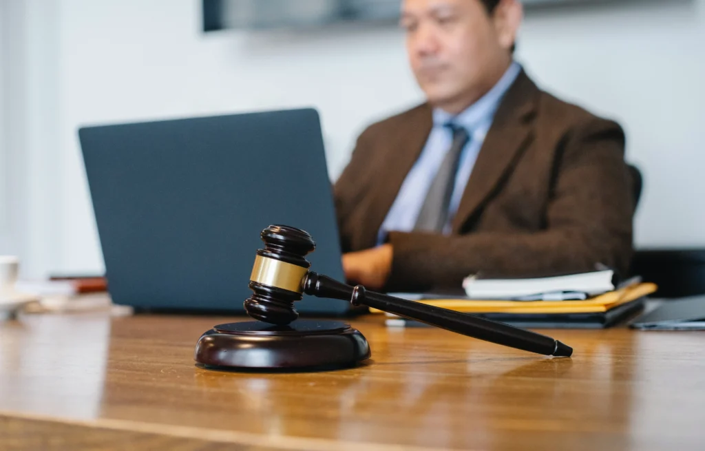 A lawyer working at his desk on a laptop with a gavel on it