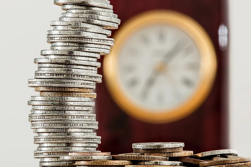 Coins stacked in front of a clock on the wall